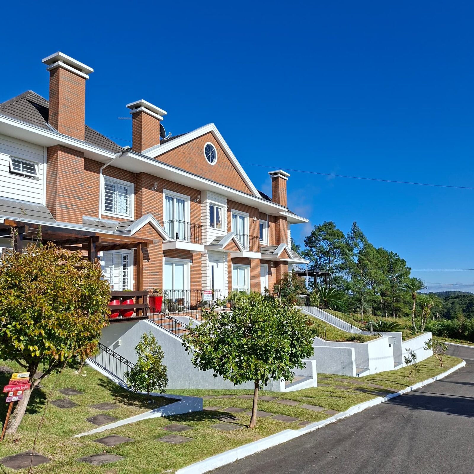 Jardim residencial em casa de tijolos com gramado, árvores e muros brancos
