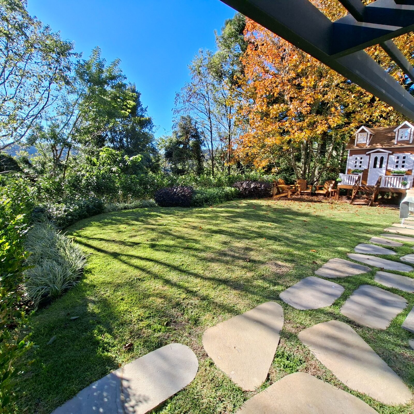 Jardim residencial com gramado aparado, canteiros e caminho de pedras executado pela Braun Paisagismo