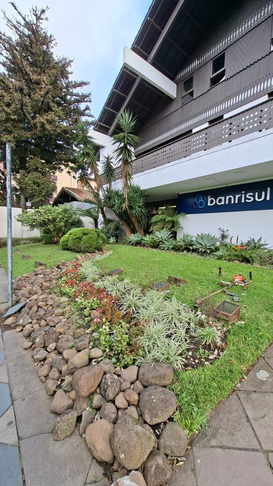 Paisagismo executado em frente à agência do Banrisul, com canteiros, pedras e gramado